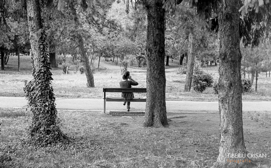 O femeie vorbeste la telefon pe o banca din parc